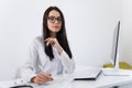 Woman healthcare worker doing some paperwork and using computer while working at doctor`s office. Royalty Free Stock Photo