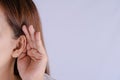 Woman hearing loss or hard of hearing and cupping her hand behind her ear isolate grey background, Deaf concept
