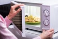 Woman Heating Food In Microwave