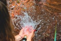 Woman heaving fun with hosepipe splashing water