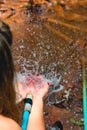 Woman heaving fun with hosepipe splashing water