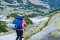 Woman with heavy backpack and a rolled sleeping pad, navigating a trekking trail in Retezat mountains part of Carpathians.