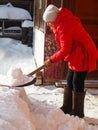 A woman after a heavy snowfall cleans the area from snow with a shovel. Sunny winter day.Clear sky. The consequences of a snowfall