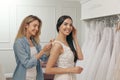 Woman helping bride wear wedding dress