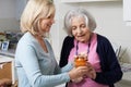 Woman Helping Senior Neighbor To Remove Jar Lid