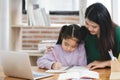 A woman is helping a young girl with her homework