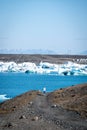 person walking by the icebergs near the water on a sunny day