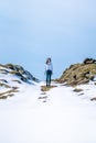 a woman standing on a rocky mountain top covered in snow Royalty Free Stock Photo