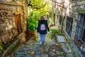 Woman with her back to walking through a narrow alley with stone houses in the village of Patones de Arriba, Madrid.