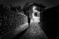 Woman with her back turned home at night on a narrow and lonely street,