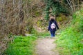 Woman with her back turned walking through the forest on a dirt road between grass and trees with bare branches Royalty Free Stock Photo