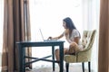 Young woman at her bright cozy and beautiful home working on desk with laptop