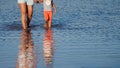 A woman and her child wade across a flooded pond. Their silhouettes are reflected in the water. Copy space.