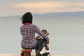 Woman and her dog against the sea watching the sunset. Royalty Free Stock Photo