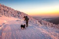 Woman with her dog hiking in winter mountain during sunset Royalty Free Stock Photo
