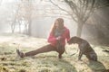 Woman and her dog stretching outdoor. Fitness girl and her pet working out together. Royalty Free Stock Photo