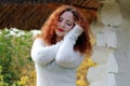 Portrait a woman model with closed eyes. She stands near the old house in a white knitted sweater. Royalty Free Stock Photo