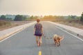 Woman with her golden retriever dog walking on the public road Royalty Free Stock Photo