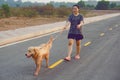 Woman with her golden retriever dog walking on the public road Royalty Free Stock Photo