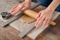 Woman with her hands rolls pastry for a cookie with a rolling pi
