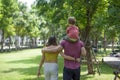 A woman, her husband and her son walk together, enjoying nature in a sunny park with trees and a walking path. View from behind Royalty Free Stock Photo