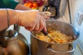 A woman in her 60s cooks lazy cabbage and rice cabbage rolls in a large pot in the kitchen