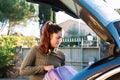 Woman in her 30s with red hair putting her luggage in the trunk of the car. Royalty Free Stock Photo