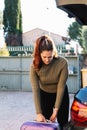 Woman in her 30s taking her luggage to put it in the trunk of the car. Royalty Free Stock Photo