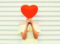 Woman hides head red air balloon heart shape over white