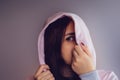 The woman hides her face behind the hood. Stylish female posing in a hoodie. Portrait of a young woman covering her face