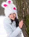 Woman hiding behind tree in winter