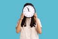 Woman hiding face behind big wall clock, time management, schedule and business meeting appointment, Royalty Free Stock Photo