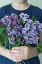 Woman hiding head in bouquet lilac flowers over colorful blue background Royalty Free Stock Photo