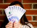 Woman hiding her face with a range of fifthy tousand pesos bill and bricks