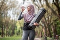 Woman in hijab and activewear drinking water at park Royalty Free Stock Photo