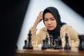 Woman in hijab thinking before stepping while playing chess