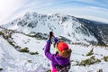 Woman hikeing in the snowy mountains with a phone and snowshoes. and backpack