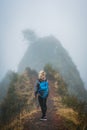 Woman hiker with backpack on the narrow misty path of mountain ridge on Santo Antao island, Cape Verde Royalty Free Stock Photo