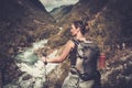 Woman hiker with backpack standing on the edge of the cliff with epic wild mountain river view.