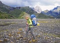 Woman hiker with backpack walking up the trail with beautiful mountain peaks view landscape