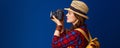 Woman hiker on blue background taking photo with digital camera