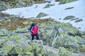 Woman hiker with bright fuchsia shirt, trekking poles, heavy backpack, on a trail in Retezat mountains part of Carpathians