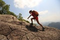 woman hiker climbing rock on mountain peak cliff