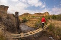 Woman hiker crossing hanging footbridge, suspended on stream, in the majestic Golden Gate Highlands National Park, South Africa.