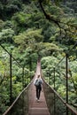 Woman hiker crossing suspension bridge deep inside rain forest Royalty Free Stock Photo