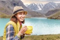 Woman hiker eats lunch and enjoys a view of the blue lake in the mountains, camping food concept Royalty Free Stock Photo