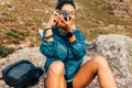 Woman hiker filming scenery while taking a break on a hill during climbing