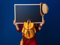 Woman hiker isolated on blue background showing blank board