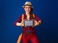 Woman hiker isolated on blue showing tablet PC blank screen