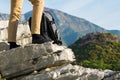 Woman hiker legs stands on the edge of the mountain cliff against beautiful mountains peak Royalty Free Stock Photo